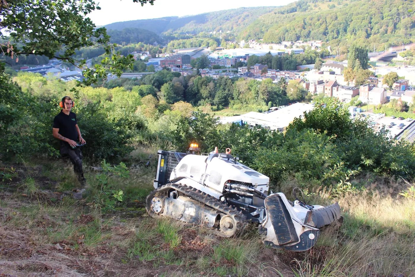 Opérateur pilotant une débroussailleuse télécommandée sur une pente