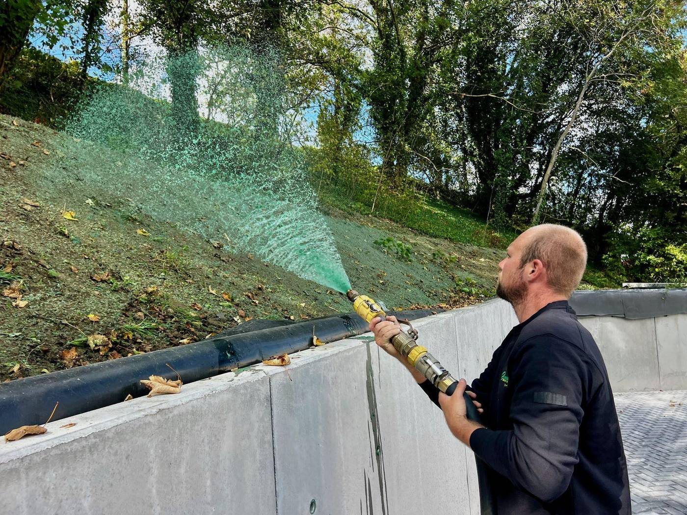 Opérateur projetant de l'hydrosemis sur un talus