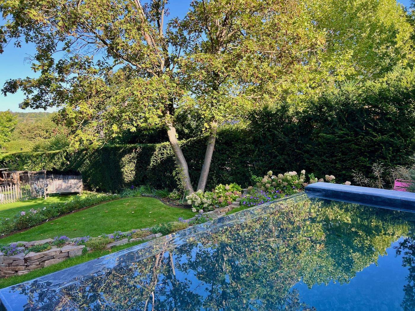 Jardin avec bassin, haies taillées et grands arbres
